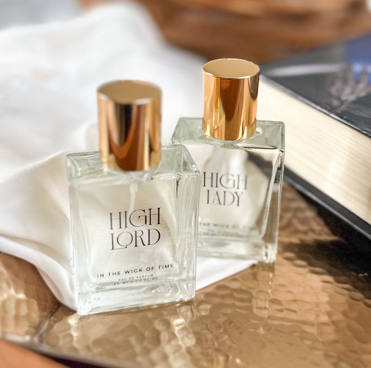 High Lord and High Lady perfume bottles in front of a book